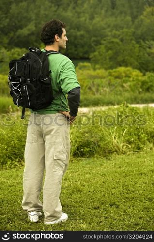 Side profile of a mid adult man standing with a backpack