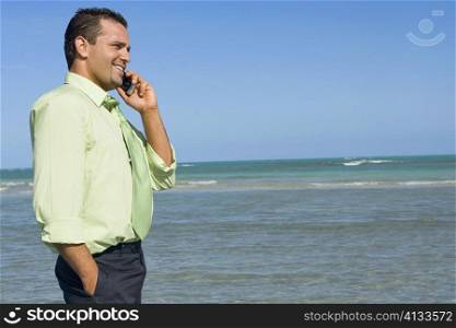 Side profile of a mid adult man talking on a mobile phone on the beach