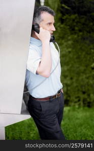 Side profile of a mid adult man talking on a pay phone