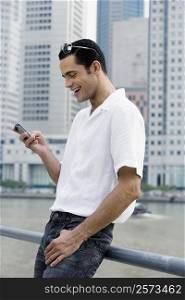 Side profile of a mid adult man text messaging and smiling