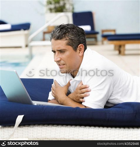 Side profile of a mid adult man using a laptop