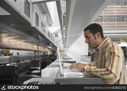 Side profile of a mid adult man using a laptop at an airport