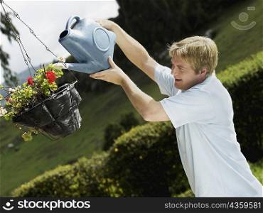 Side profile of a mid adult man watering a potted plant