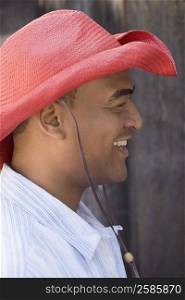 Side profile of a mid adult man wearing a cowboy hat and smiling