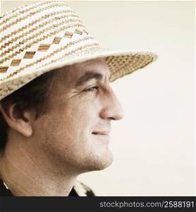 Side profile of a mid adult man wearing a straw hat