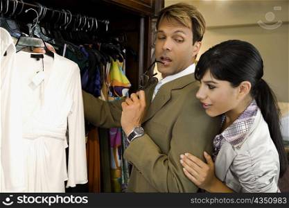 Side profile of a mid adult man with a young woman choosing a dress in a clothing store