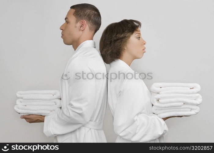 Side profile of a mid adult man with a young woman holding stacks of towels