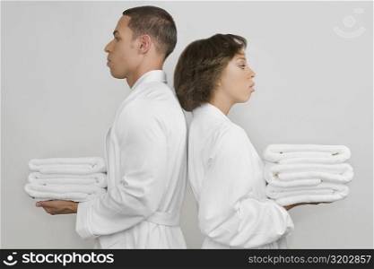 Side profile of a mid adult man with a young woman holding stacks of towels