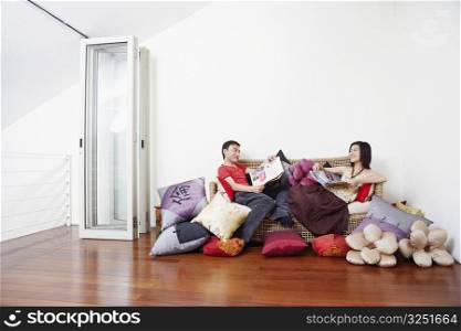 Side profile of a mid adult man with a young woman reclining on a couch and looking at each other