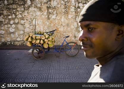 Side profile of a mid adult man with coconuts in a rickshaw in the background, Santo Domingo, Dominican Republic