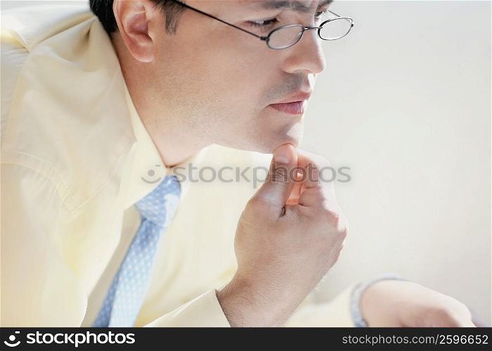 Side profile of a mid adult man with his hand on his chin
