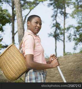 Side profile of a mid adult woman carrying a basket and holding an oar