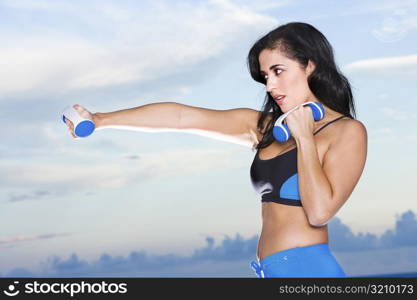 Side profile of a mid adult woman exercising with dumbbells