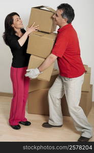 Side profile of a mid adult woman helping a mid adult man hold cardboard boxes