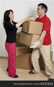 Side profile of a mid adult woman helping a mid adult man hold cardboard boxes