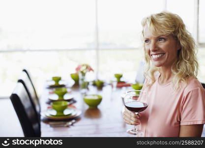 Side profile of a mid adult woman holding a glass of wine and smiling