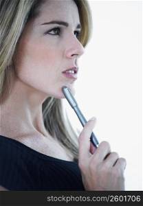 Side profile of a mid adult woman holding a pen and thinking