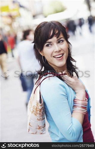 Side profile of a mid adult woman holding a shopping bag and smiling