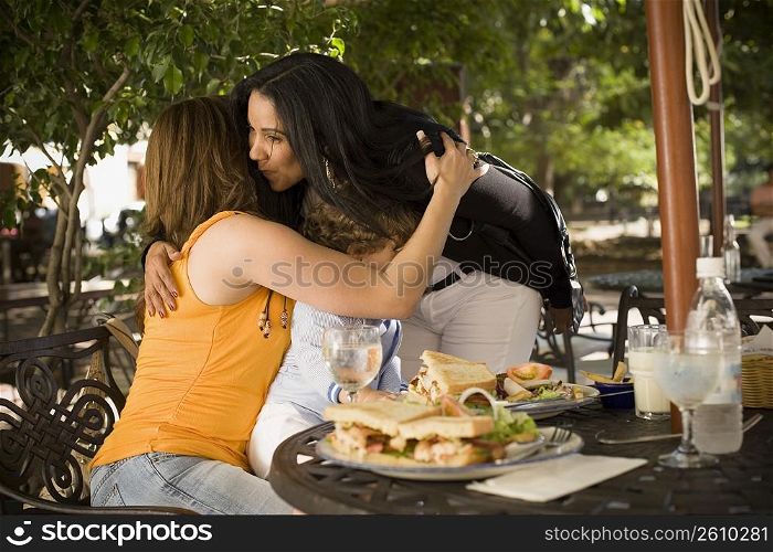 Side profile of a mid adult woman hugging and kissing her friend in a restaurant, Santo Domingo, Dominican Republic