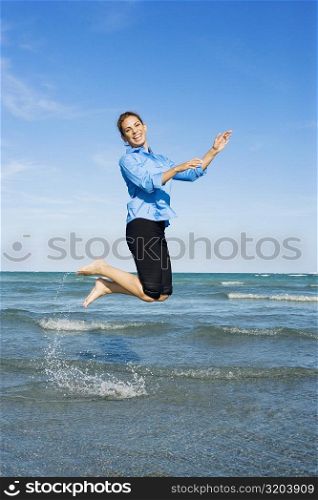 Side profile of a mid adult woman jumping on the beach