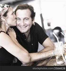 Side profile of a mid adult woman kissing a mid adult man and smiling