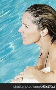 Side profile of a mid adult woman leaning at the poolside