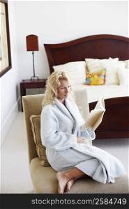 Side profile of a mid adult woman sitting on a chair and reading a book