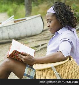 Side profile of a mid adult woman sitting on the beach and reading a book