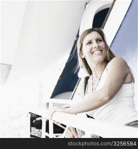 Side profile of a mid adult woman standing on the staircase of a cruise ship and smiling