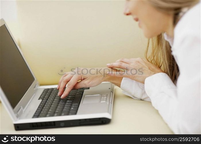 Side profile of a mid adult woman using a laptop and smiling
