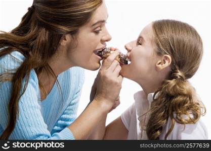 Side profile of a mother and her daughter eating a pastry