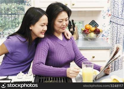 Side profile of a mother and her daughter reading a newspaper
