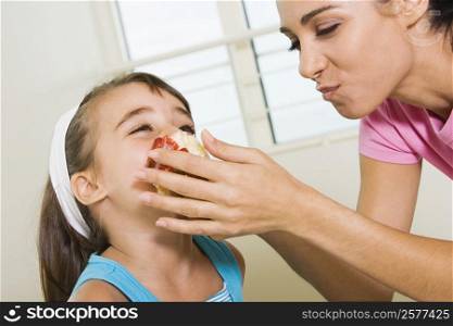 Side profile of a mother feeding her daughter