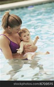 Side profile of a mother playing with her baby boy in a swimming pool