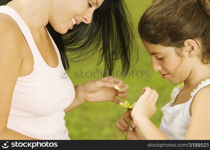 Side profile of a mother plucking a flower petal with her daughter