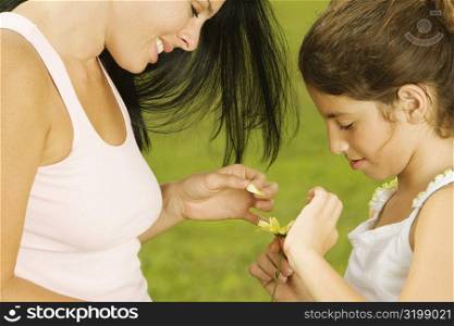 Side profile of a mother plucking a flower petal with her daughter