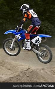 Side profile of a motocross rider performing jump on a motorcycle