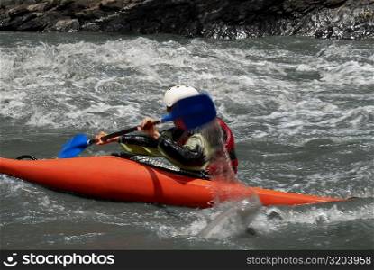 Side profile of a person kayaking in a river