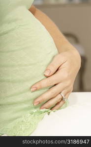 Side profile of a pregnant woman touching her abdomen