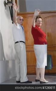 Side profile of a senior couple waving their hands and smiling