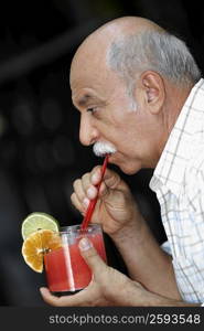 Side profile of a senior man drinking a glass of juice