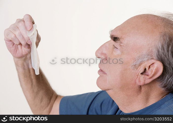 Side profile of a senior man holding a condom