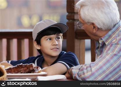 Side profile of a senior man with his grandson at a restaurant