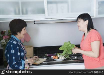 Side profile of a senior woman and her daughter preparing food in a kitchen