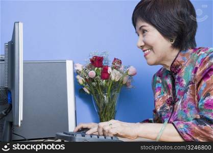 Side profile of a senior woman using a computer and smiling