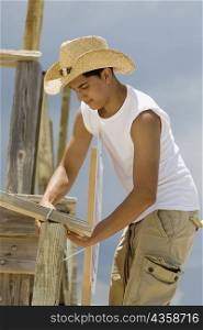 Side profile of a teenage boy building a wooden structure