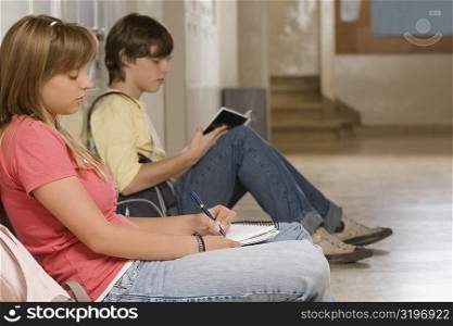 Side profile of a teenage girl and a teenage boy studying