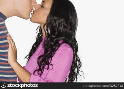 Side profile of a teenage girl and a young man kissing each other