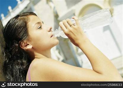 Side profile of a teenage girl drinking water from a bottle