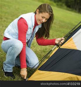 Side profile of a teenage girl putting up a tent